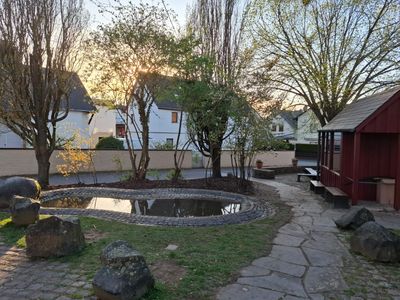 Der Weiherplatz in Dieblich-Berg mit Teich, Bäumen und Fachwerkhäusern in der Abendsonne